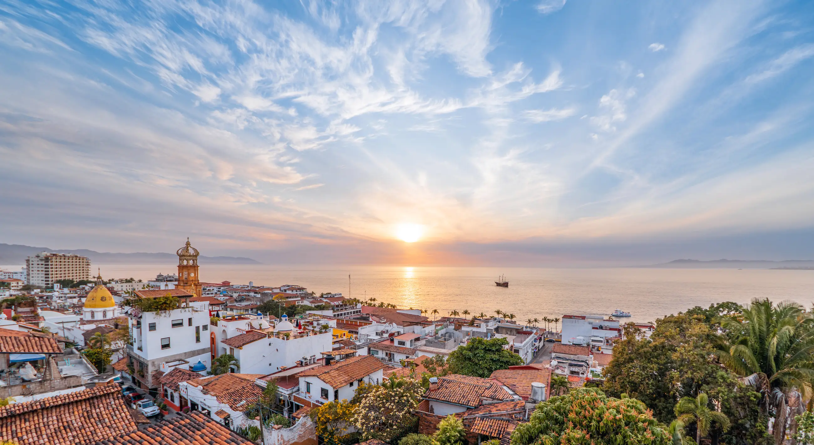 Atardecer sobre la bahía de Puerto Vallarta, con la torre de la parroquia de Guadalupe y el Pacífico al fondo